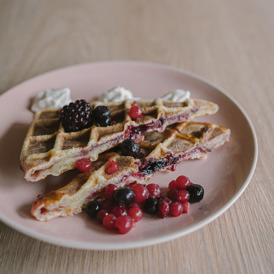 Gaufre fourrée aux fruits rouges, posée dans une assiette rose